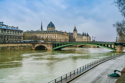 Arch bridge over river against cloudy sky