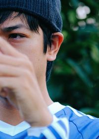 Close-up of man looking away against trees