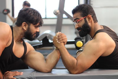 Male friends arm wrestling at gym