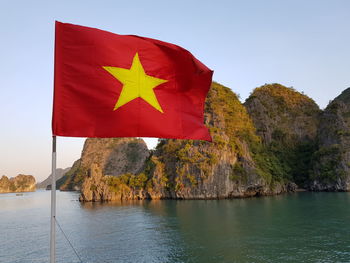 Scenic view of red flag by sea against sky