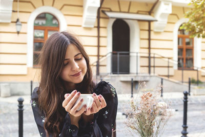 Young woman having coffee while sitting at outdoor cafe in city