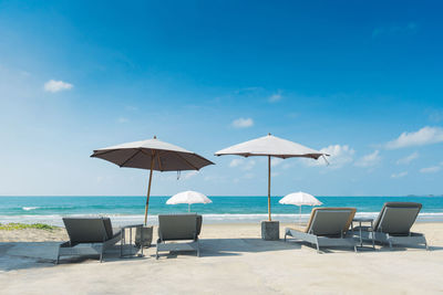 Deck chairs and parasols on beach against sky