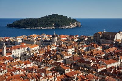 High angle view of cityscape by sea against clear sky