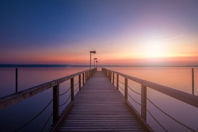 Pier over sea against sky during sunset