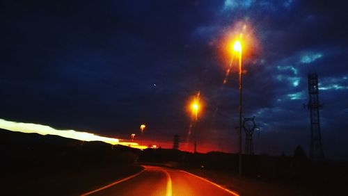 Illuminated road against sky at night