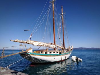 Sailboat moored on sea against clear blue sky