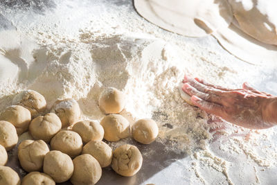 Cropped hand of person making chapatti on counter in kitchen at home