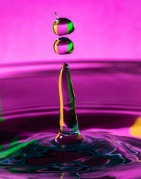 Close-up of water drop against pink background