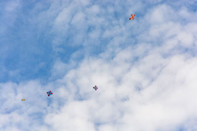 Low angle view of kites flying against sky