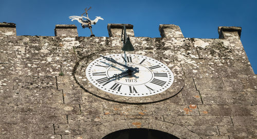 Low angle view of clock against sky