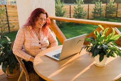 Young woman using digital tablet while sitting on table