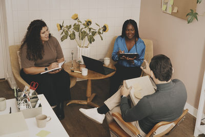 High angle view of male and female business professionals planning strategy while sitting on chairs at office