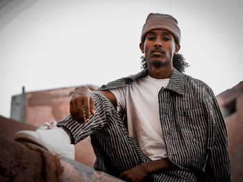 Portrait of young man sitting on wall