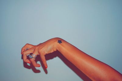 Cropped image of woman hand with tattoo against wall