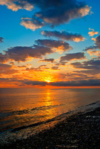 Scenic view of sea against dramatic sky during sunset