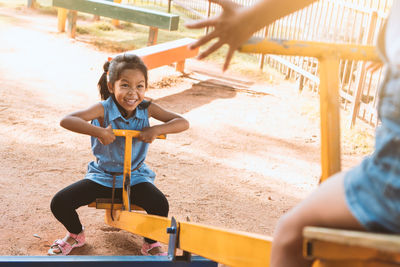 High angle view of friends playing on seesaw at playground