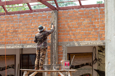 Low angle view of man working at brick wall