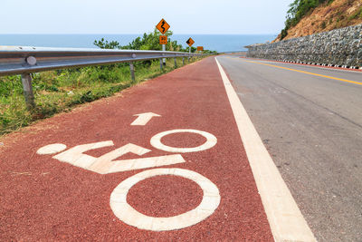 Bicycle lane sign on road against sky