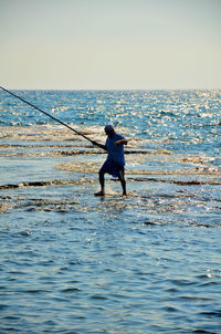 Full length of man surfing in sea against clear sky