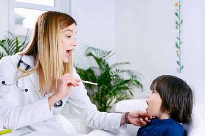 Female doctor examining boy tongue in hospital