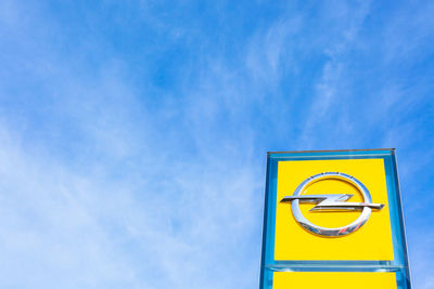 Low angle view of yellow sign against blue sky