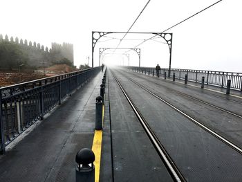 Railroad tracks on road over bridge against clear sky