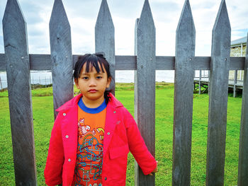 Portrait of girl standing against fence