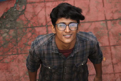 Portrait of young man standing against brick wall