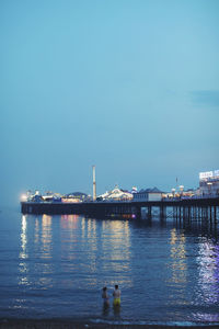 View of bridge over calm sea against blue sky