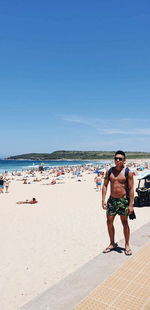 Full length of shirtless men on beach against sky