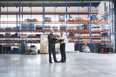 Two businessmen with clipboard on factory shop floor