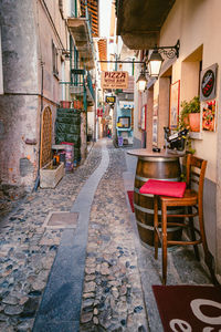 Empty chairs and tables in alley amidst buildings in city