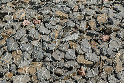 Granite gravel reinforcement of road embankment covered wth steel mesh - full-frame background