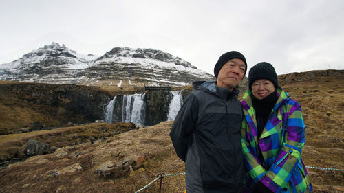 Portrait of couple standing against waterfall during winter