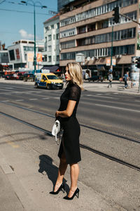 Fashionable woman standing against buildings in city