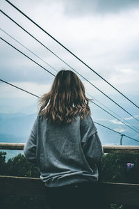 Rear view of woman standing on railway bridge against sky