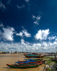 Fishing boats moored on sea against blue sky