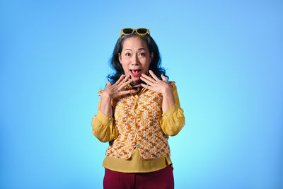 Young woman standing against blue background