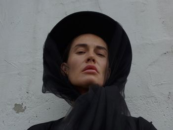 Portrait of young woman standing against wall