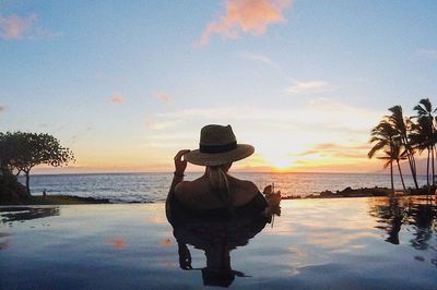 Man looking at swimming pool against sky during sunset