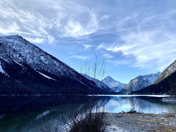 Scenic view of lake by snowcapped mountains against sky