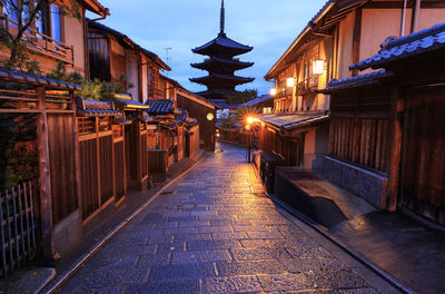 Illuminated street amidst buildings in city at night