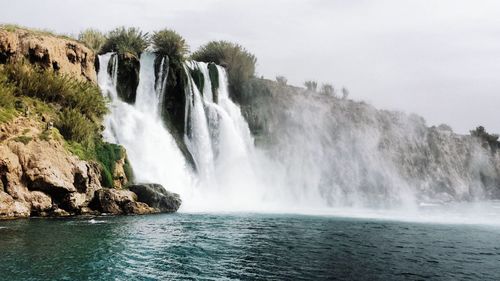 Scenic view of waterfall against sky