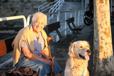 Portrait of smiling man with dog sitting outdoors