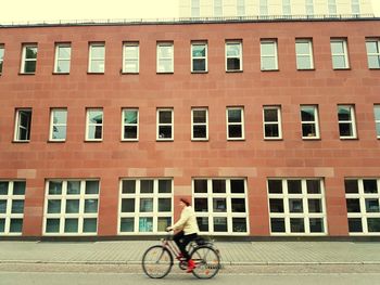 Woman riding bicycle on building in city