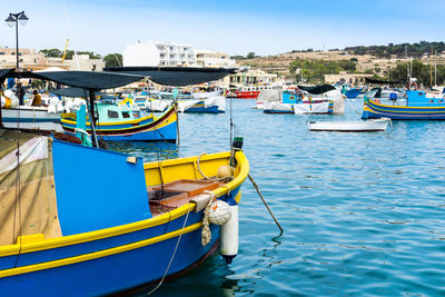 Boats moored at harbor against blue sky