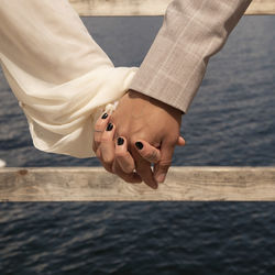 Low portrait shot of man and woman holding hands in front of a fence on a pier