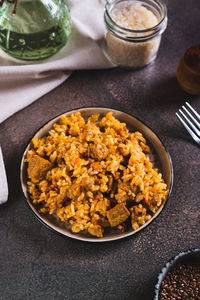 Traditional spicy pilaf with rice and meat on a plate on the table vertical view