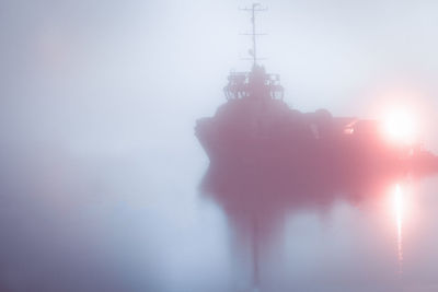 Low angle view of silhouette foggy weather against sky