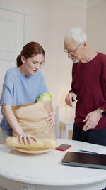 Nurse holding grocery bag with senior man at rehab center